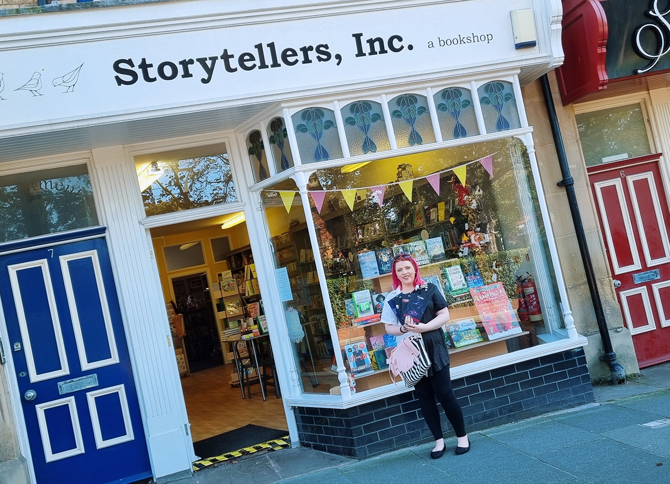 K.R Jones standing outside of bookshop holding her published MSMI series books.